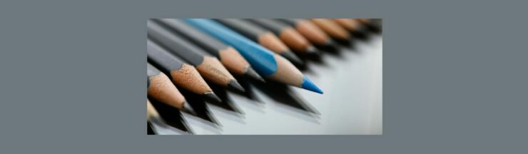 How to Write a Good Blog Post Title Tips to Stand Out in the Crowd (4). Medium gray background. Line of dark gray pencils, one shiny blue standing out, a little further out the the rest of the crowd.