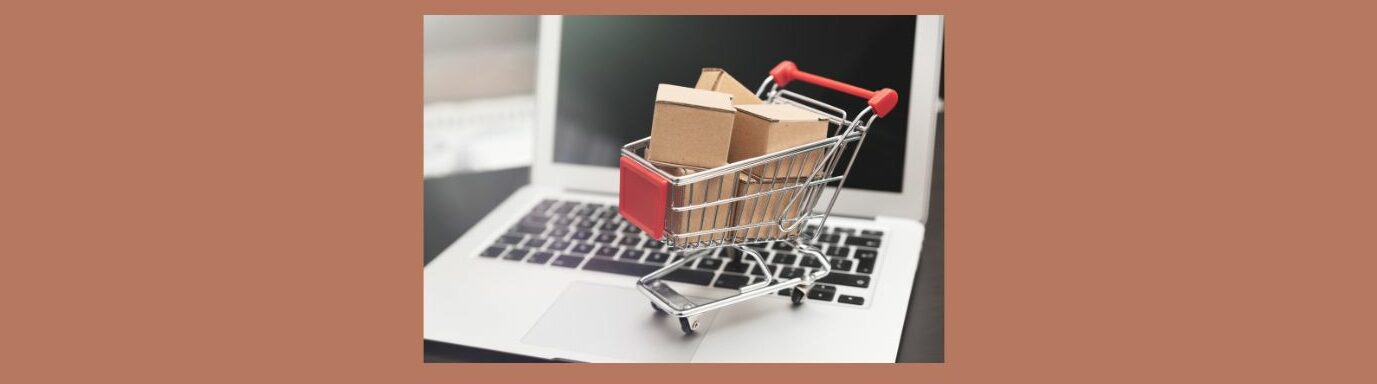 E-Commerce Insights Online Business Model Series (4)
Light medium brown background.
Open silver laptop, black screen, black keyboard. Silver shopping cart with red square on front and red handles. 5 brown boxes stacked inside cart.