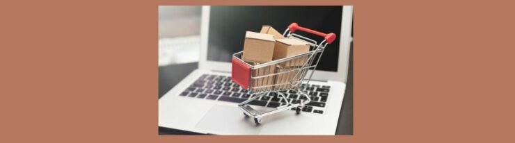 E-Commerce Insights Online Business Model Series (4) Light medium brown background. Open silver laptop, black screen, black keyboard. Silver shopping cart with red square on front and red handles. 5 brown boxes stacked inside cart.