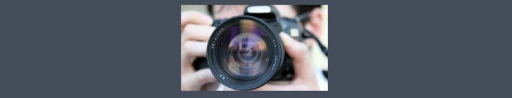 How to Make Money with Stock Photography. Medium gray background. Square in the center, black camera, unfocused hands and part of a forehead with dark hair. Camera lens in the center.